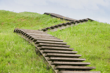 A green Zig Zag stairs uphill. Concept growth on grass