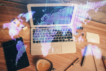 Business theme hologram drawings over computer on the desktop background. Top view. Multi exposure....
