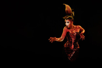 Young woman dancing in the image of Flames and Fire in a red body art emotionally posing on a black background