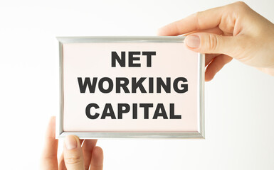 Net Working Capital text on notepad with keyboard on table.