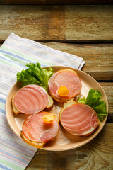 Sandwiches with ham and cherry on a wooden board on a napkin. Copy the place.