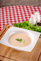 A bowl of creamy potato soup with crackers bread on white plate in italian restaurant background, top view. Vegetable cream soup. Italy food. Close up. space