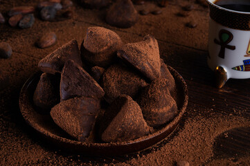 healthy delicious chocolate truffles around ingridients with natural cocoa beans,  powder, cacao butter, cane sugar and cup of coffee. healthy sweets concept. close up