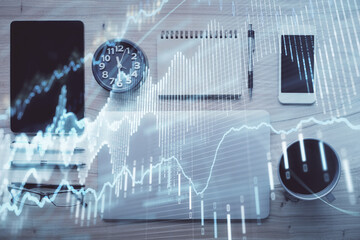 Double exposure of forex graph hologram over desktop with phone. Top view. Mobile trade platform concept.