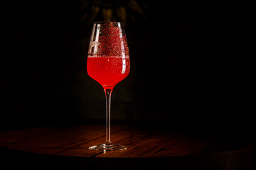 Red cocktail in a wine glass decorated with red powder.