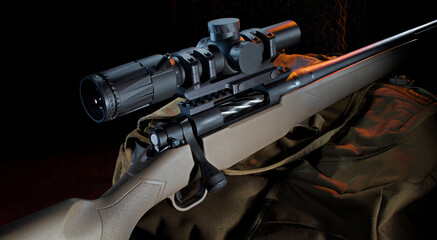 Bolt action rifle with a scope on a pack with orange rim lighting from the back