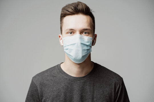 thoughtful man of Caucasian appearance, looks into each other's eyes. portrait of a young man in a blue mask that protects against the covid-19 pandemic. grey sweater on the shoulders