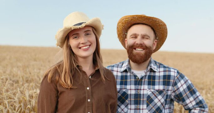 Caucasian handsome male and beautiful young woman standing in wheat field in good mood. Close up portrait of joyful couple looking at each other and smiling to camera outdoor. Family concept