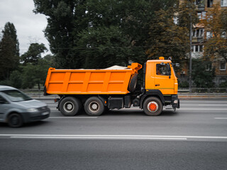 Fototapeta na wymiar Orange city utility truck in motion on the road.