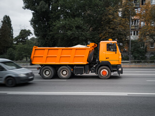 Orange city utility truck in motion on the road.