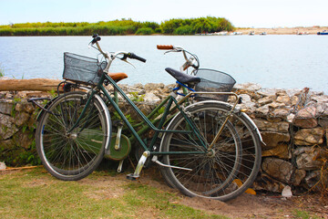 park two bicycles leaning them against a stone wall to enjoy your holidays by the sea