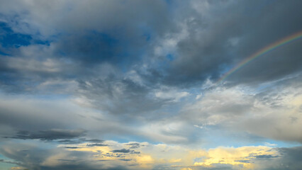 Amazing dramatic sky. Cloudy weather turning rainy. Cumulonimbus in atmosphere with rainbow.