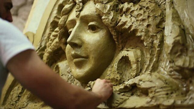 Sculptor create clay model of a mascaron ornament in restoration workshop