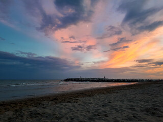 Colorful sunset at the adriatic sea on the beach in Italy. Sunset sky and clouds in the evening