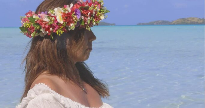 Beautiful woman wearing flower crown in Bora Bora near turquoise water