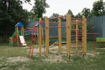 playground with horizontal bars, ladders and exercise equipment on the street in green grass against the background of a playground