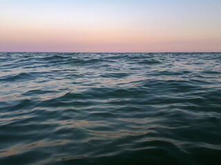 Scenic view of sunset on the sea with waves in motion.