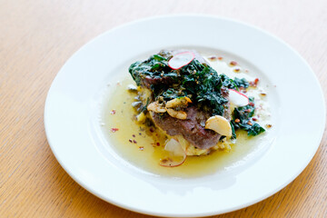 Beef Medallions with Mashed Potatoes and Spiced Oil. Close up of a rare roasted juicy medallion of beef fillet seasoned with salt and spices and garnished with fresh herbs.