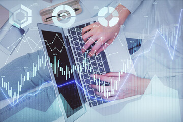Double exposure of woman hands working on computer and forex graph hologram drawing. Top View. Financial analysis concept.
