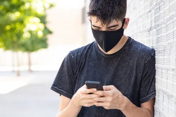 Fototapeta na wymiar young teenage man with mask and mobile phone on the street