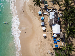 Aerial drone view of surf camp at the paradise beach with palm trees, umbrellas, surfers and big...