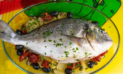 Baked sea bream with potatoes, olives and dried tomatoes.
