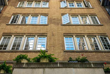 A facade of an old building with blue sky reflection in open windows