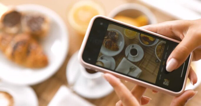 Top view close up of young female tourist hands taking picture of perfectly served breakfast on her smartphone in a luxury hotel during holidays vacation.