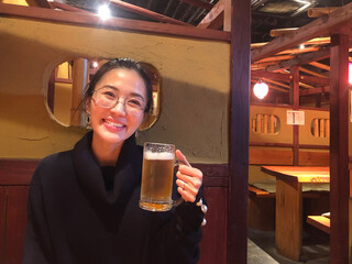 Happy smiling woman enjoy eating beer at classic restaurant in Japan