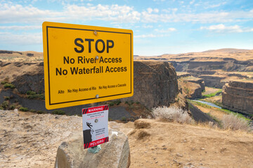 A warning sign on the trail above the Palouse Falls canyon state park warning hikers of danger and...