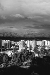Amazing cloudy sky over Santiago skyline, Santa Lucía hill and the snowed The Andes Mountains, and a beautiful sunlight over the city, Chile (in black and white)