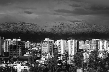Amazing cloudy sky over Santiago skyline and the snowed The Andes Mountains, and a beautiful sunlight over the city, Chile (in black and white)