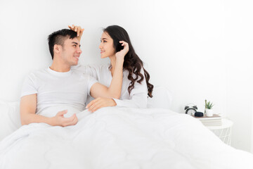 asian lover rest on bed, asian man use hand touch hair of his wife in bedroom, they feeling love and happy together, happiness honeymoon and valentine's day