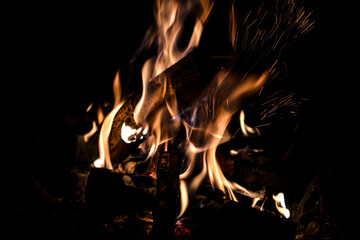 Logs burning on a camp fire pit at night. Orange flames and sparks glowing in the dark at fireplace