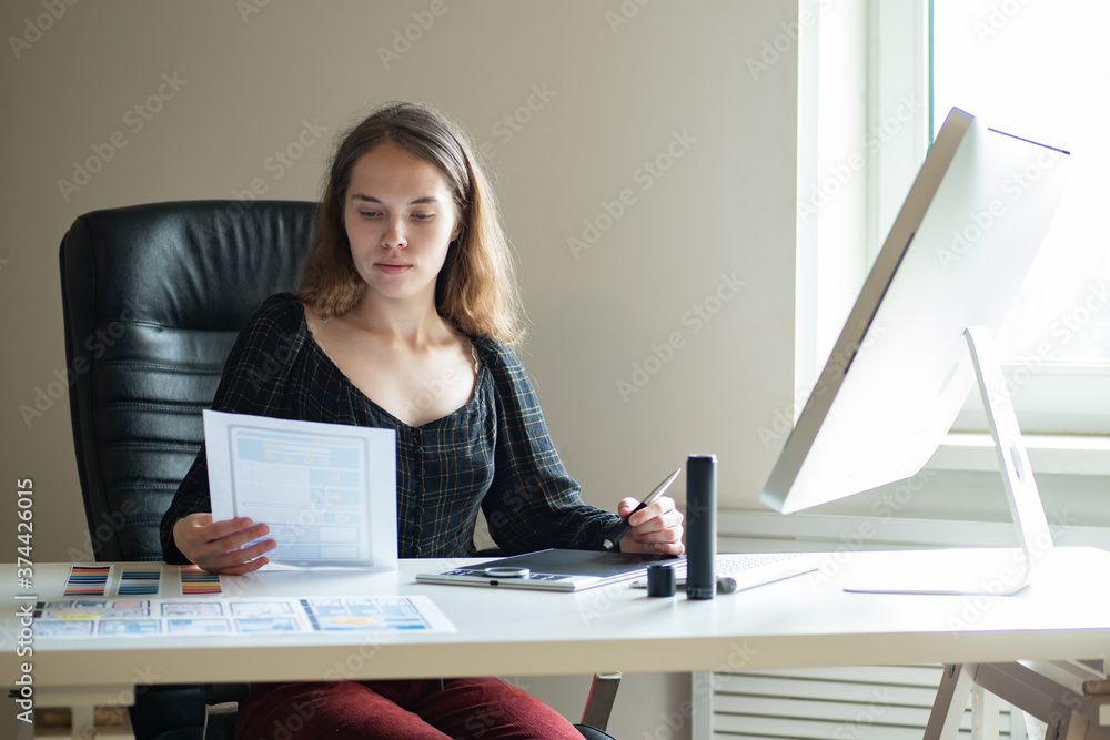 Poster application design. mobile application designer at work. girl at table draws a mockup of application