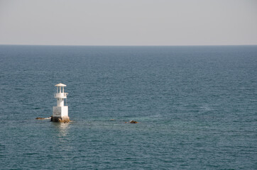 A lighthouse in the middle of the sea under the cloudy sky