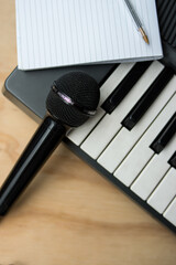 Microphone and a piano on a wooden table with a notebook 