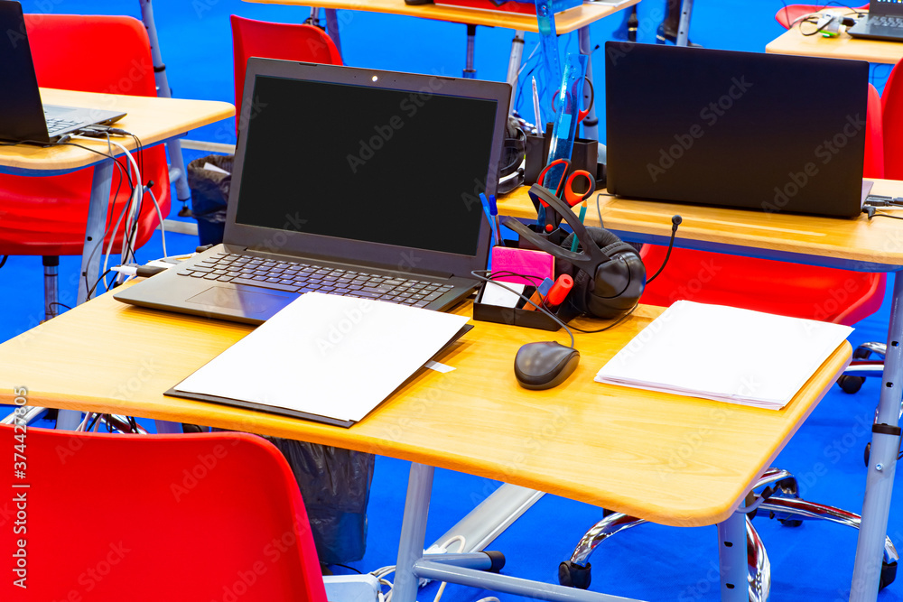 Poster computer class in college. desks with laptops, headphones and stationery. new learning technologies.