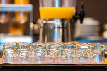 Many empty glasses in buffet restaurant, small glass water. Blurred background Juices in glass jars and breakfast buffet line. showing reflections
