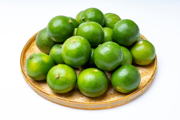 Fresh lime fruits in bamboo basket on white background