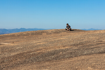 Fototapeta na wymiar Menino no alto da Pedra Grande em Atibaia, admirando a paisagem. Cena de paz e tranquilidade. 