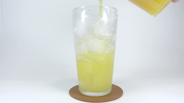 氷を入れたグラスに注ぐオレンジジュース