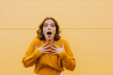 Shocked amazing girl in trendy sweater looking to camera. Indoor shot of enthusiastic brunette...
