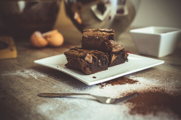 Close up of baked chocolate brownies with ingreditents in the background.