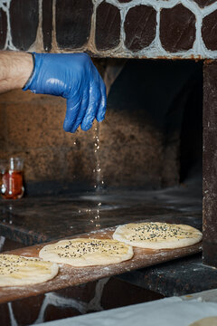 Before baking in the oven, the chef sprinkles the buns with sesame seeds. Buns for making traditional duner (Tombik Doner), oriental fast food. Close-up, copy space, traditional cuisine