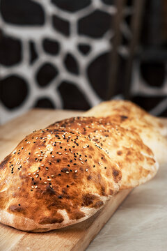 Turkish bun, tombik for making a traditional duner (Tombik Doner), oriental fast food. Tombic with sesame and caraway seeds. Fresh baked buns cool on table. Close-up, copy space, traditional cuisine