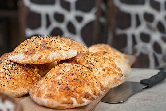 Turkish bun, tombik for making a traditional duner (Tombik Doner), oriental fast food. Tombic with sesame and caraway seeds. Fresh baked buns cool on table. Close-up, copy space, traditional cuisine