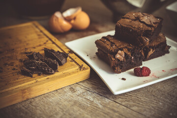 Close up of baked chocolate brownies with ingreditents in the background.