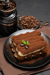 Classic tiramisu dessert and coffee grinder on ceramic plate on concrete background