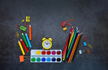 school accessories and alarm clock on black background. Back to school concept. School supplies on blackboard. flat lay. copy space